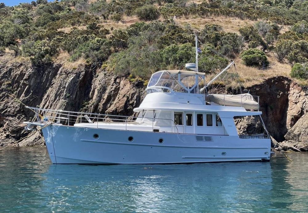 Bateau au mouillage dans une crique rocheuse bordée de pins
