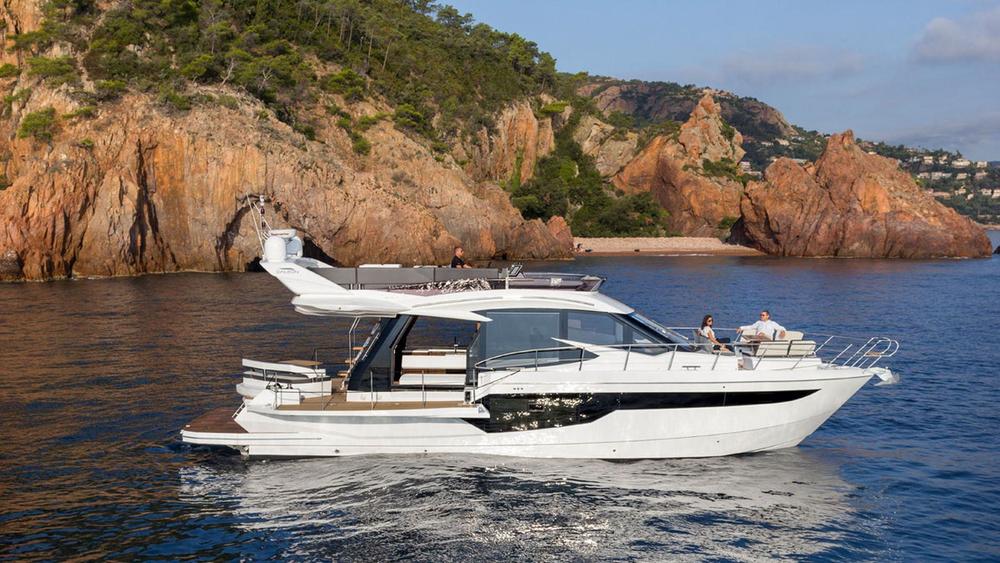 Yacht au mouillage devant des falaises de roche rouge
